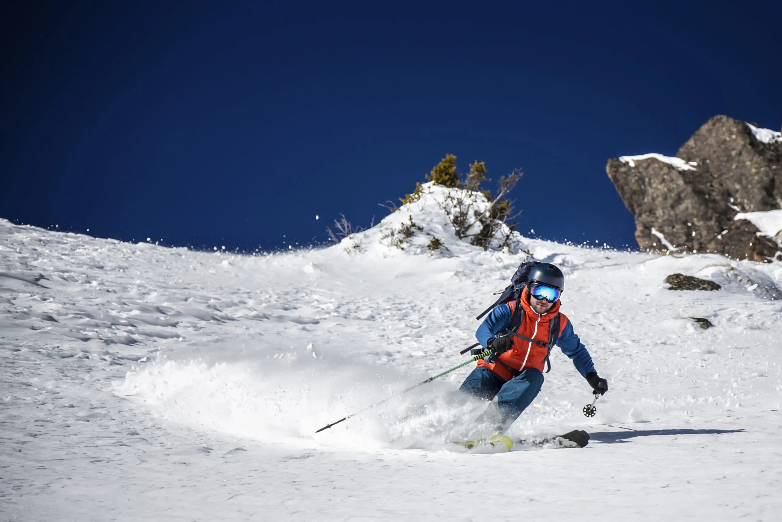 Expert freeride skier charging donw through steep slope