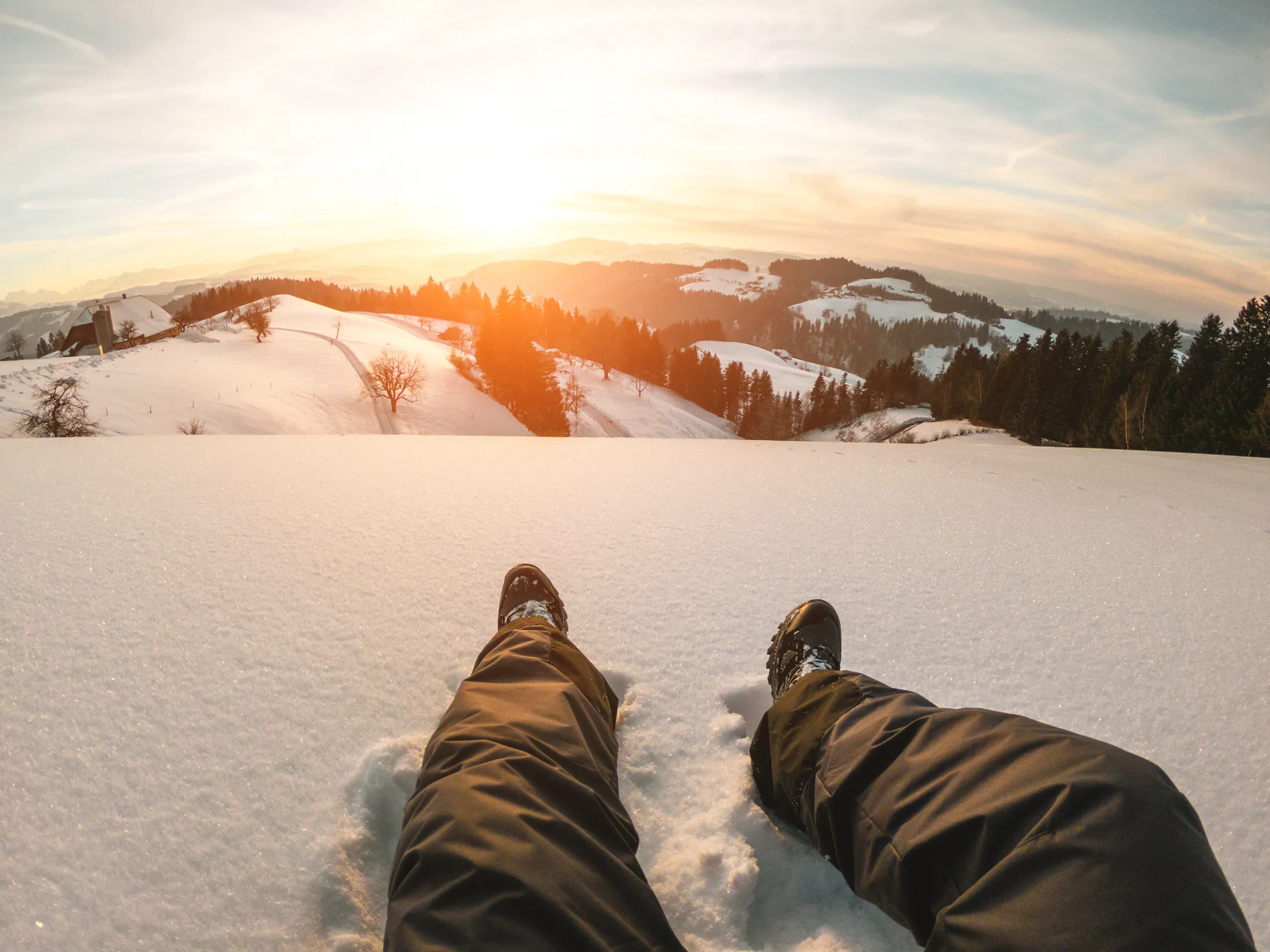 Pov of young man looking the sunset on snow high mountains - Winter vacation concept - Focus on his feet