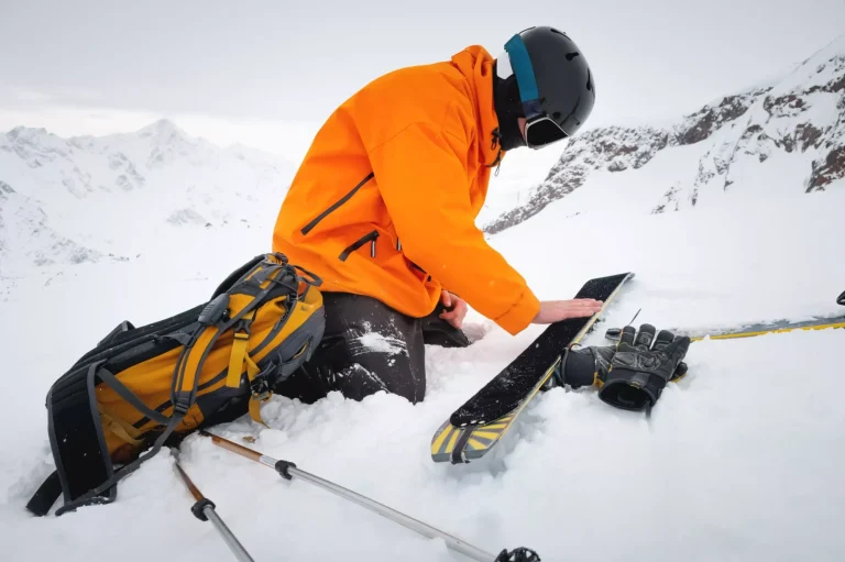 Ski tourist repairs skis in snowy mountains. Snow and winter activities, ski touring in the mountains.